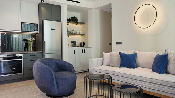 Uma sala de estar moderna com um sofá, uma mesa de centro redonda e uma poltrona singular.