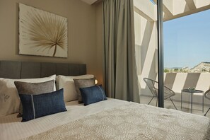 Ein Hotelzimmer mit einem großen Bett, Blick auf die Stadt und einem Balkon mit Sitzgelegenheiten.