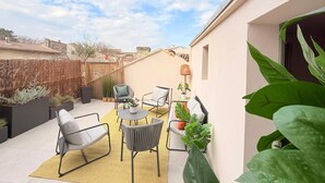 Un patio con mobiliario exterior, una mesa redonda y plantas en macetas.