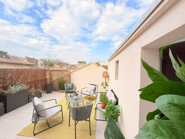 A patio with outdoor furniture, a round table, and potted plants.