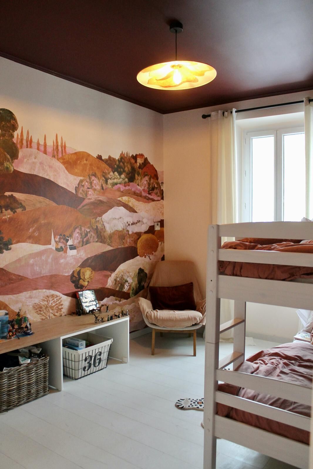 A child's room with bunk beds, a mural, and a window.