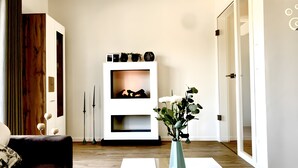 A modern living room with a sofa, a white console table with decorative items, a vase with flowers, and a wooden floor. - Holiday Home Mena at Lake Diemelsee (Diemelsee)