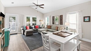 A spacious living room with a sofa, coffee table, and a dining area with a table and chairs. - 3BR home in Shorewalk: Pool, Grill, Arcade + Free Tix: Dolphin Cruise & More! (Panama City Beach)