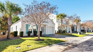 A row of white houses with green shutters, a paved driveway, and a well-maintained lawn. - 3BR home in Shorewalk: Pool, Grill, Arcade + Free Tix: Dolphin Cruise & More! (Panama City Beach)