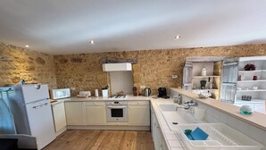 Une cuisine compacte avec un mur en pierre, un four encastré, un four à micro-ondes et un évier.