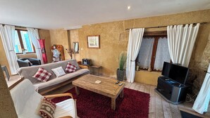 Un salon confortable avec un canapé, un fauteuil et un téléviseur.