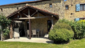 Un bâtiment en pierre doté d’un patio couvert avec des espaces de détente en plein air.