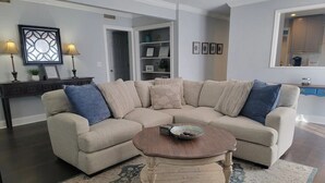 A living room with a beige sectional sofa, a round coffee table, and a patterned rug. - Old Village Home w/ Huge Patio-Beach & CHS in 10 Mins! STR#ST260017 BL#20124322 (Mount Pleasant)