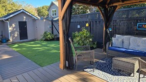 A wooden deck with a covered seating area, a small lawn, and a wooden fence. - Old Village Home w/ Huge Patio-Beach & CHS in 10 Mins! STR#ST260017 BL#20124322 (Mount Pleasant)