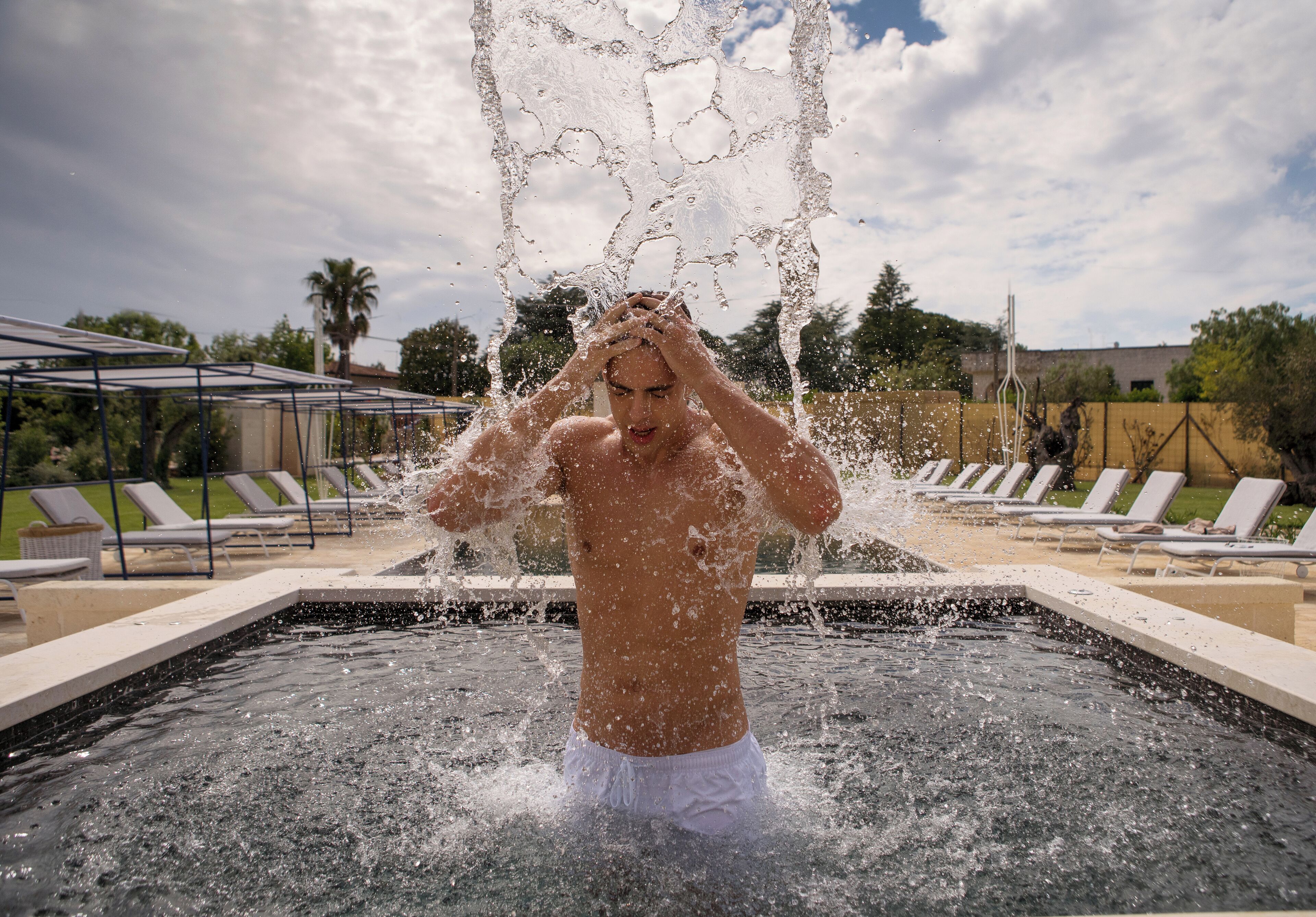 A man in a swimming pool with water splashing around him.