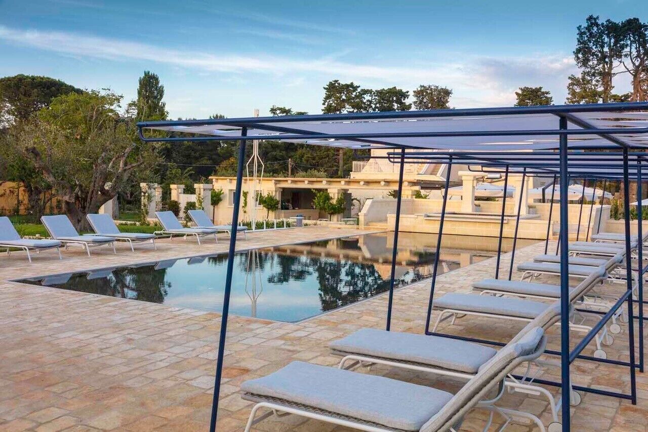 En swimmingpool med solstolar och en pergola.