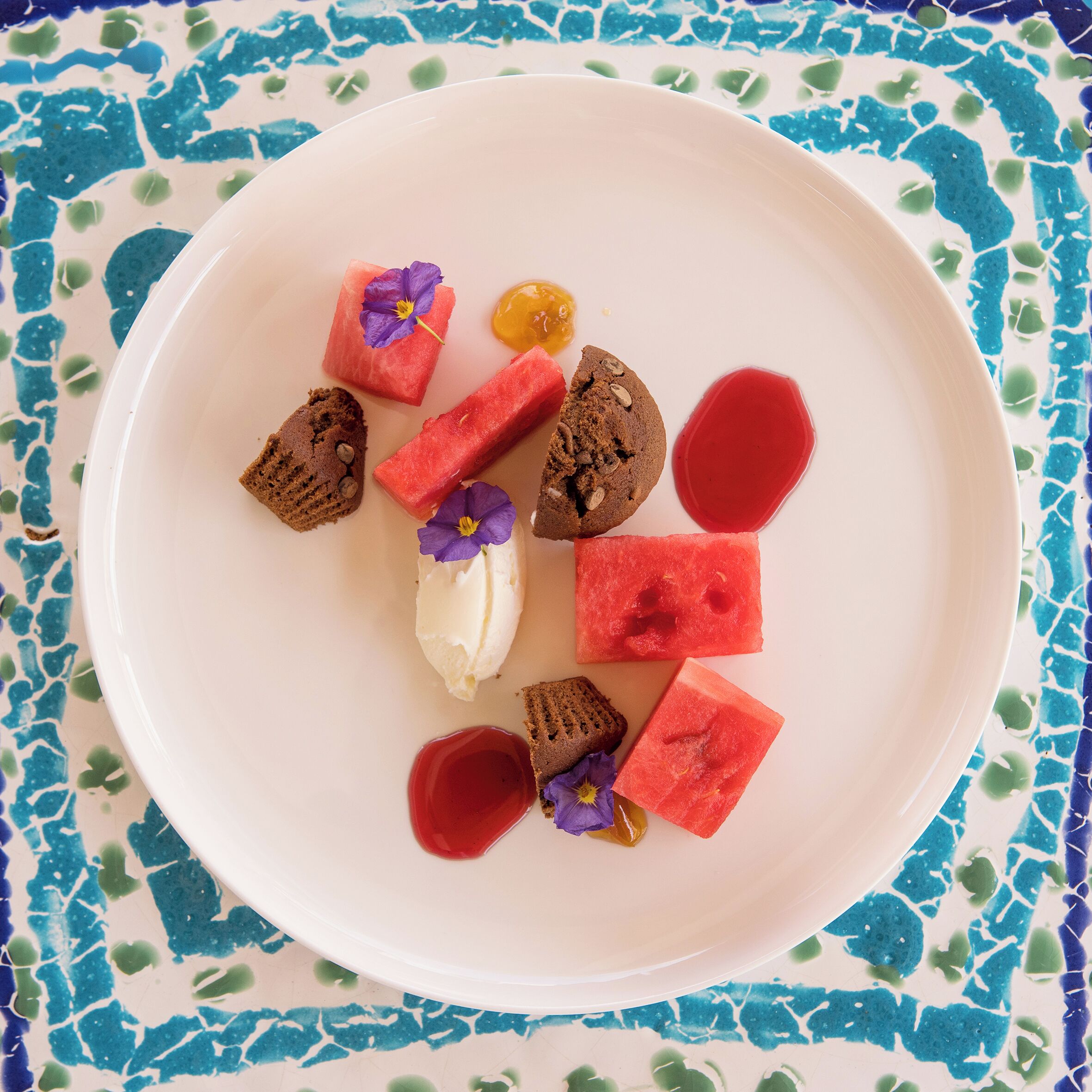 A dessert plate with various items including watermelon, cookies, and a dollop of cream.