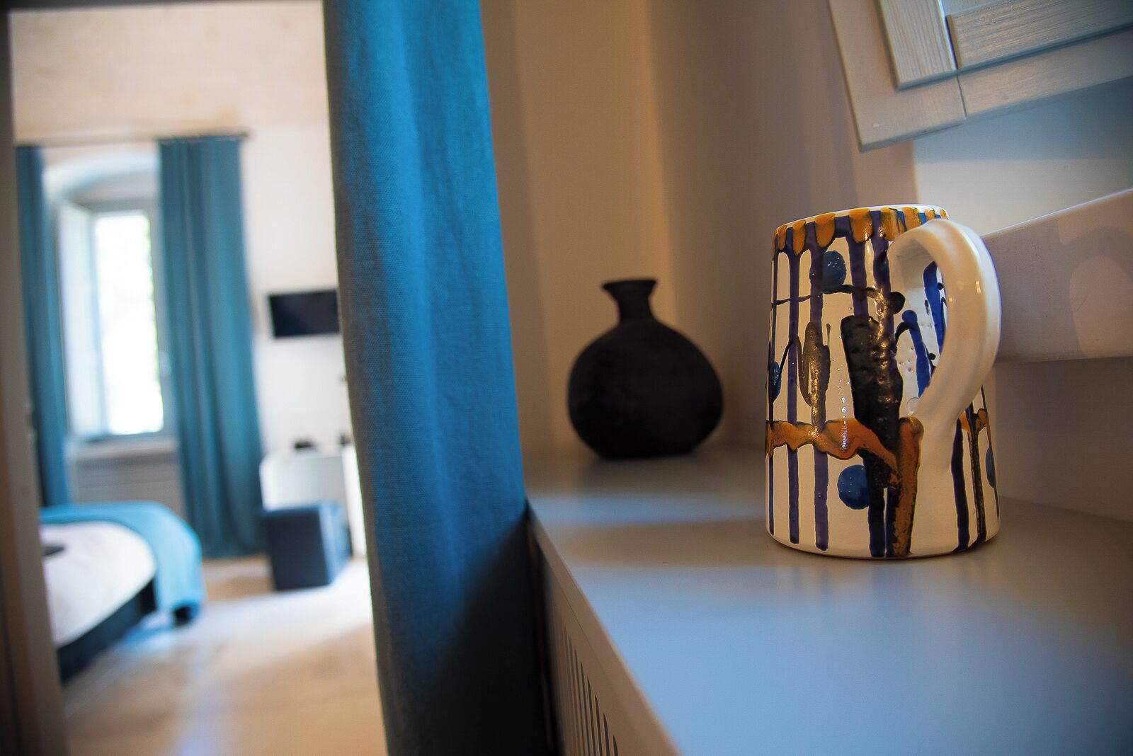 Una stanza con un letto, un vaso e una tazza su un tavolo.