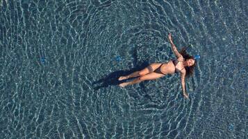 Una persona flotando en una piscina cristalina con reflejos y ondulaciones.