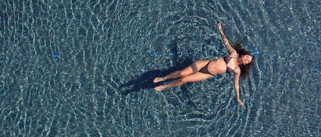 Una persona flotando en una piscina cristalina con reflejos y ondulaciones.