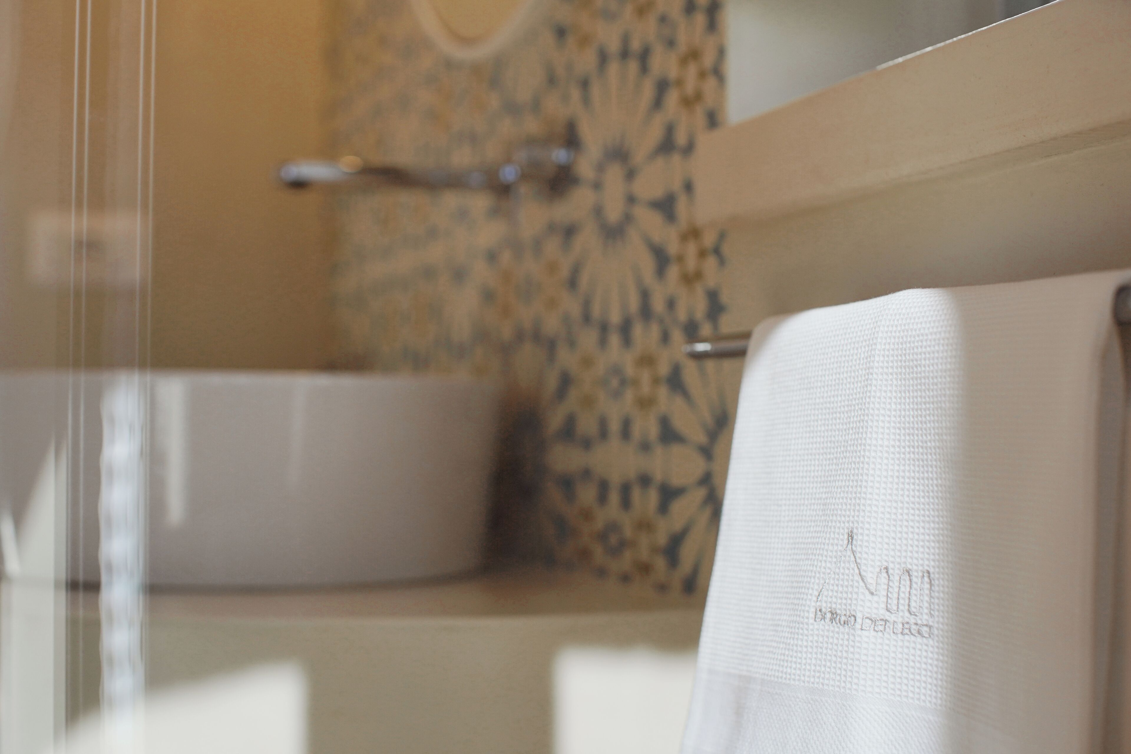 Un bagno con un lavandino bianco, un asciugamano su un porta asciugamani e una parete decorata.