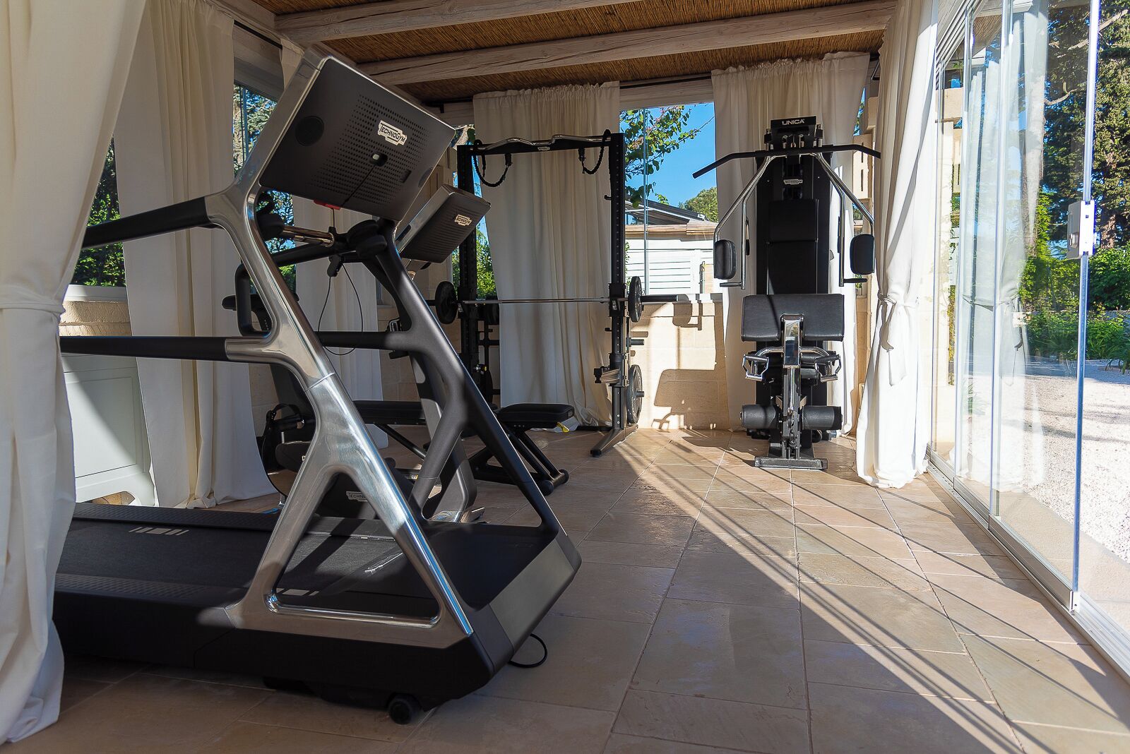 Un gimnasio con cintas de correr, una prensa de banca y una estructura para sentadillas.