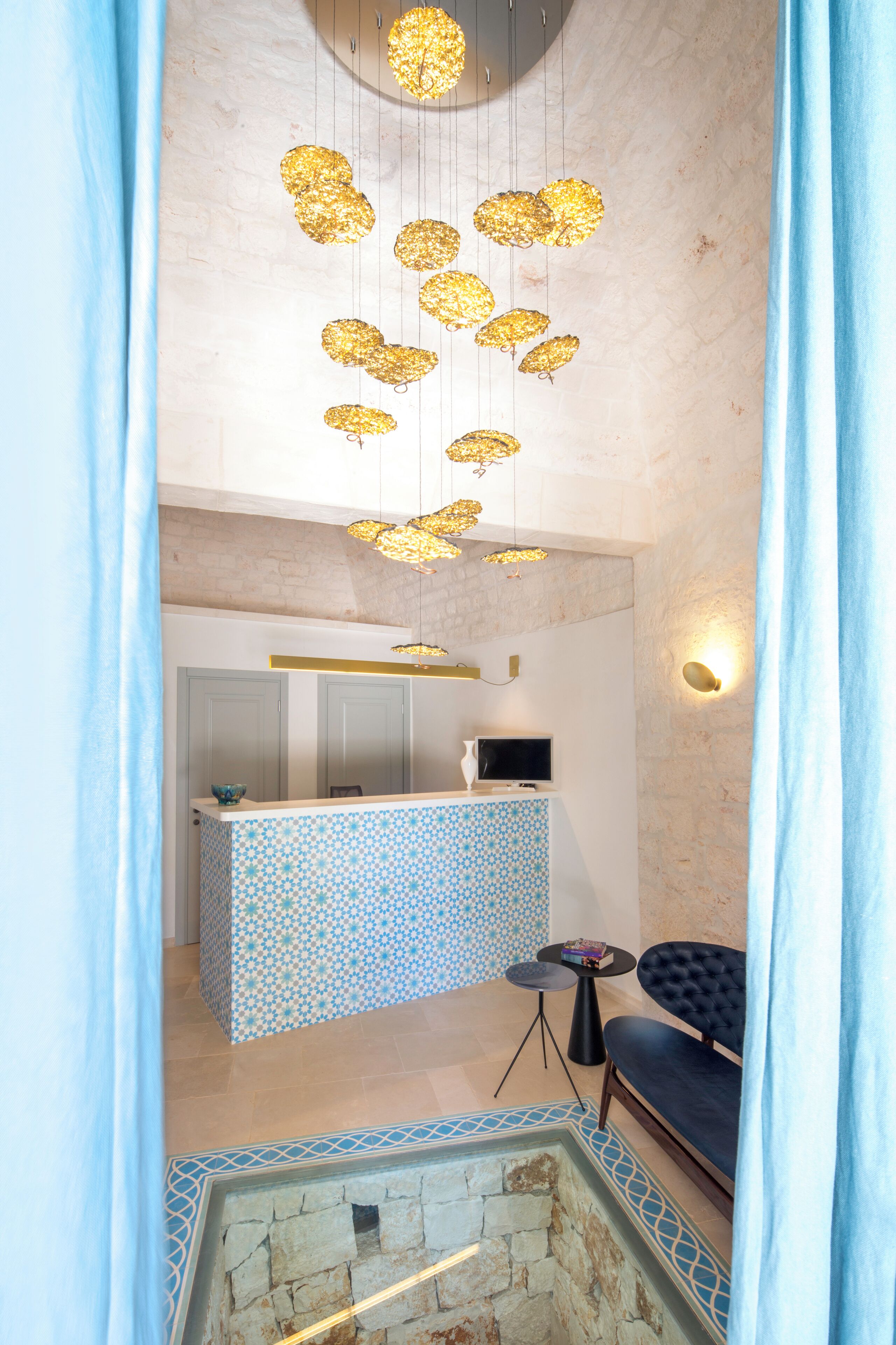 Un intérieur moderne avec un comptoir d’accueil à motifs, une cheminée en pierre et un canapé bleu.