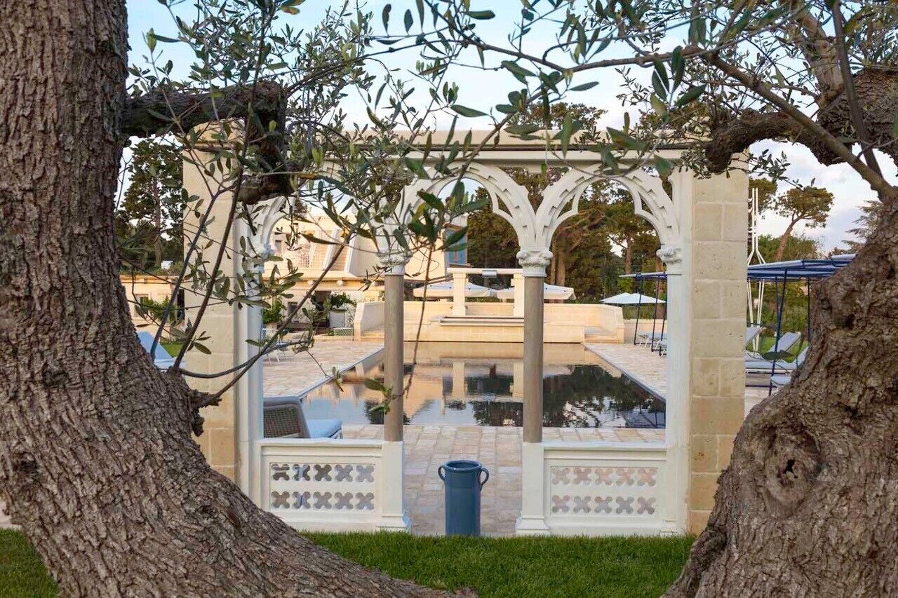 A gazebo with a tiled floor and a blue trash bin in front.