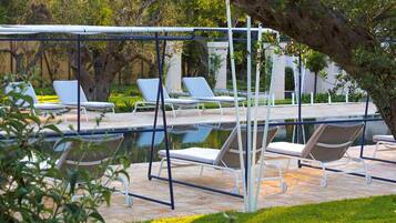 A pool area with lounge chairs and a swing set.