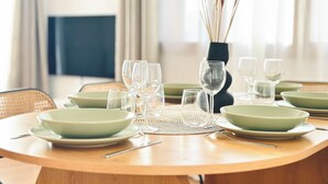 A dining table set with green plates, clear glasses, and a vase with tall grasses. - Direct metro to central Paris 3-rooms apartment with Panoramic View-Free Park (Saint-Denis)