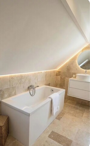 A modern bathroom with a freestanding bathtub, a vanity with a mirror, and a towel rack.