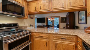 A kitchen with wooden cabinets, stainless steel appliances, and granite countertops. - I1 Gore Creek Meadows 4 Bedroom Townhouse (Vail)