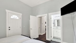 A bedroom with a bed, a door leading to a bathroom, and a TV mounted on the wall.
