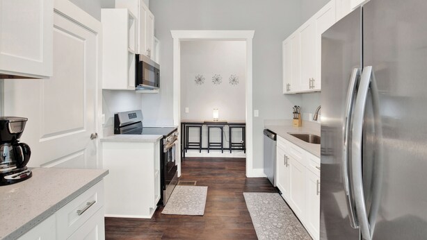 A modern kitchen with white cabinetry, stainless steel appliances, and a central island.
