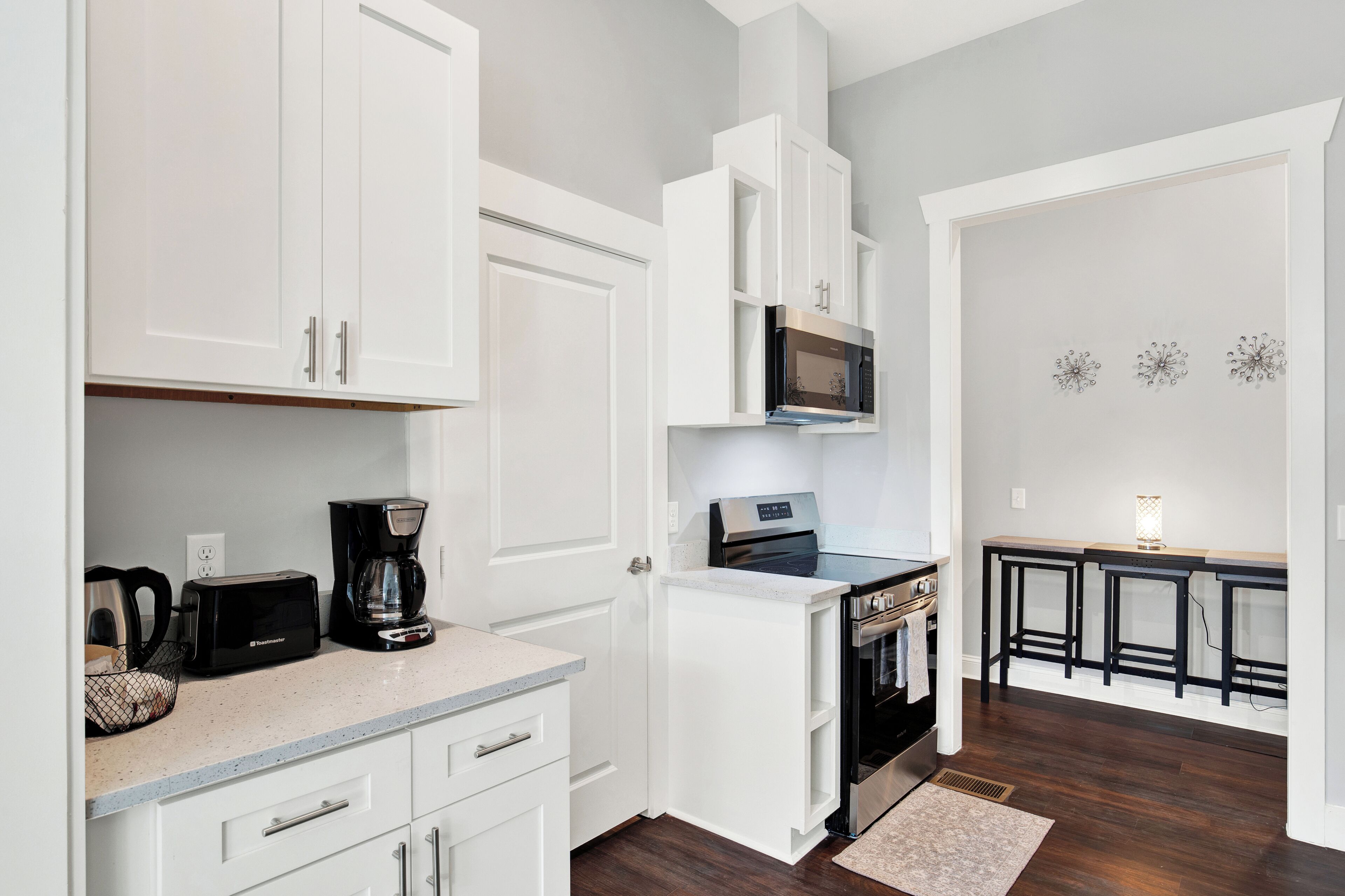 A compact kitchen with white cabinetry, a microwave, a toaster, and a coffee maker.