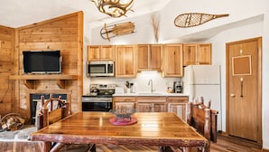 Una cocina rústica con armarios de madera, una mesa de comedor de madera y un televisor montado.
