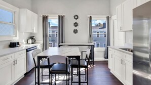Eine moderne Küche mit weißen Schränken, einer Marmorarbeitsplatte und einem Edelstahl-Kühlschrank.