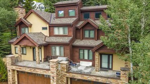 A multi-story house with a stone facade, multiple windows, and a balcony with outdoor furniture. - 1175 B Casolar Del Norte 3 Bedroom Duplex (Vail)