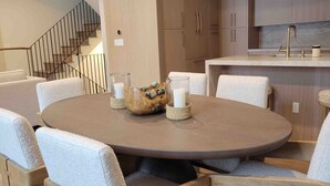 A dining area with a round table, cushioned chairs, and a decorative centerpiece. - 1175 B Casolar Del Norte 3 Bedroom Duplex (Vail)