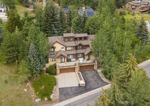 A multi-story house with a stone facade, multiple windows, and a garage. - 1175 B Casolar Del Norte 3 Bedroom Duplex (Vail)