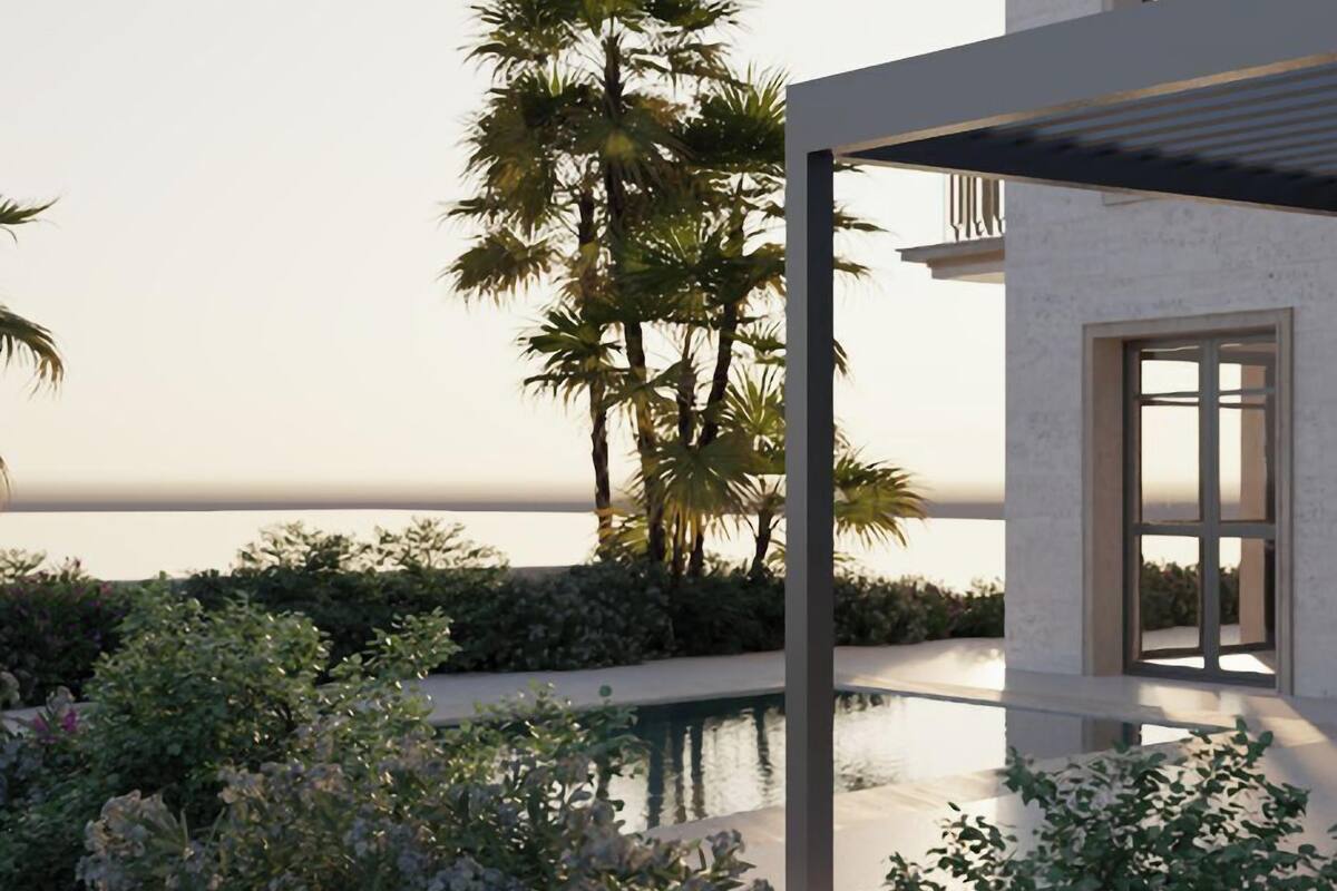 Un bâtiment moderne doté d’une piscine, entouré d’une végétation luxuriante et de palmiers, et offrant une vue sur une étendue d’eau.
