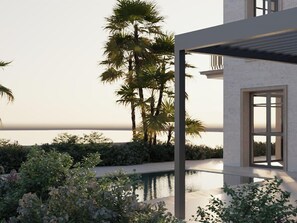 Ein modernes Gebäude mit Schwimmbad, umgeben von üppiger Vegetation und Palmen, mit Blick auf ein Gewässer.