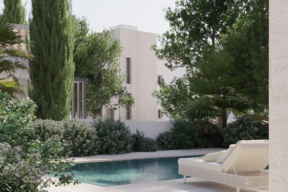 Un espace piscine extérieur moderne, avec un fauteuil de détente blanc et un bâtiment en arrière-plan.