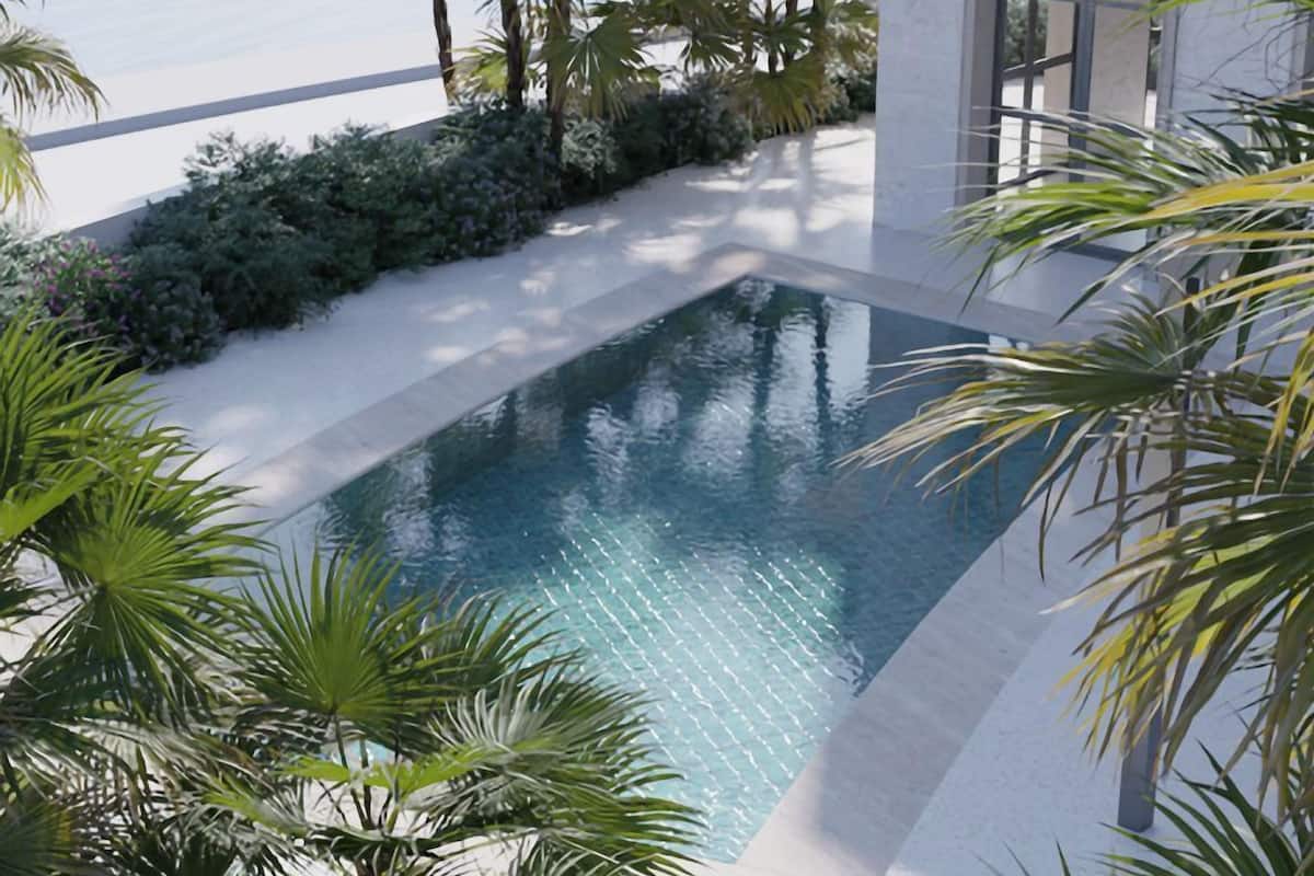 Un espace piscine moderne avec une eau cristalline, entouré d’une végétation luxuriante et bordé d’une terrasse blanche.