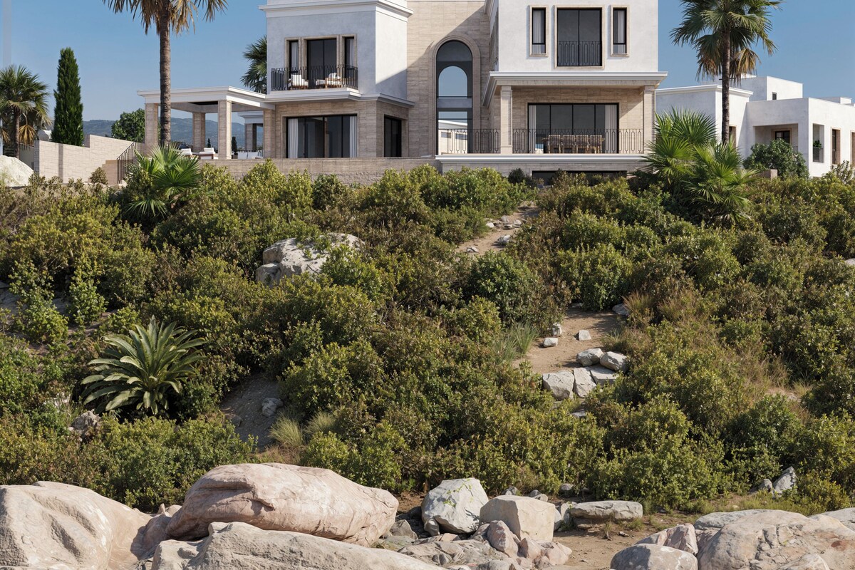 Une maison côtière moderne dotée d’un grand balcon, d’un chemin pavé de pierres et d’un rivage rocheux.