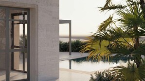A modern building with a glass door, a pool, and tropical plants. - Lantana Villas and Hotel (Pegeia)