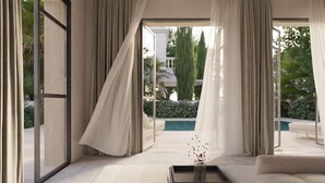 A modern living room with large windows, a sofa, and a coffee table. - Lantana Villas and Hotel (Pegeia)