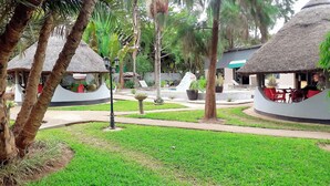 A resort with thatched-roof huts, a central pathway, and surrounding greenery. - Acamms Lodge (Lusaka)
