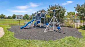 Ein Spielplatz mit Rutsche, Schaukeln und einer Kletterkonstruktion.