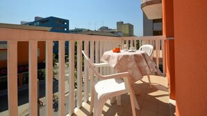 Ein Balkon mit Tisch und Stühlen, Blick auf die Stadt, und ein Gebäude mit blauer Fassade.