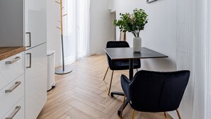 Et moderne køkken med hvide skabe, en træbordplade og en sort stol med gyldne ben.