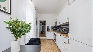Et moderne køkken med hvide skabe, en træbordplade og en sort stol.