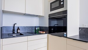 Een moderne keuken met witte kasten, een zwart aanrecht, een ingebouwde magnetron en een oven.