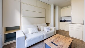 Een moderne woonkamer met een bank, een salontafel en een keukenhoek met kasten en een aanrecht.