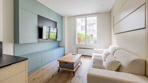 Een modern appartement met keuken, een eethoek en een woonkamer met een bank en een tv aan de muur.